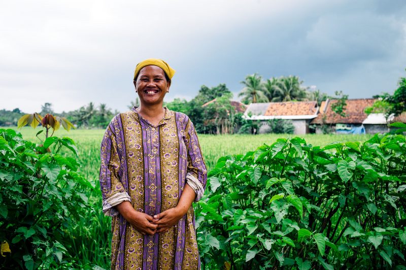 Woman smiles while standing in a field in Indonesia
