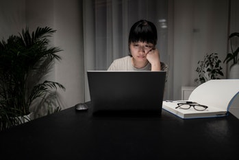 Young Asian women focused on working from home, working late at night on laptops at home. Home Offic...